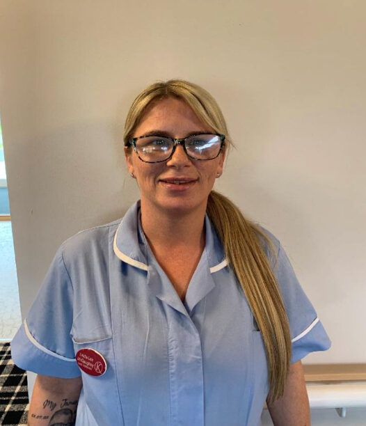 woman with blonde hair and glasses in light blue nurses uniform