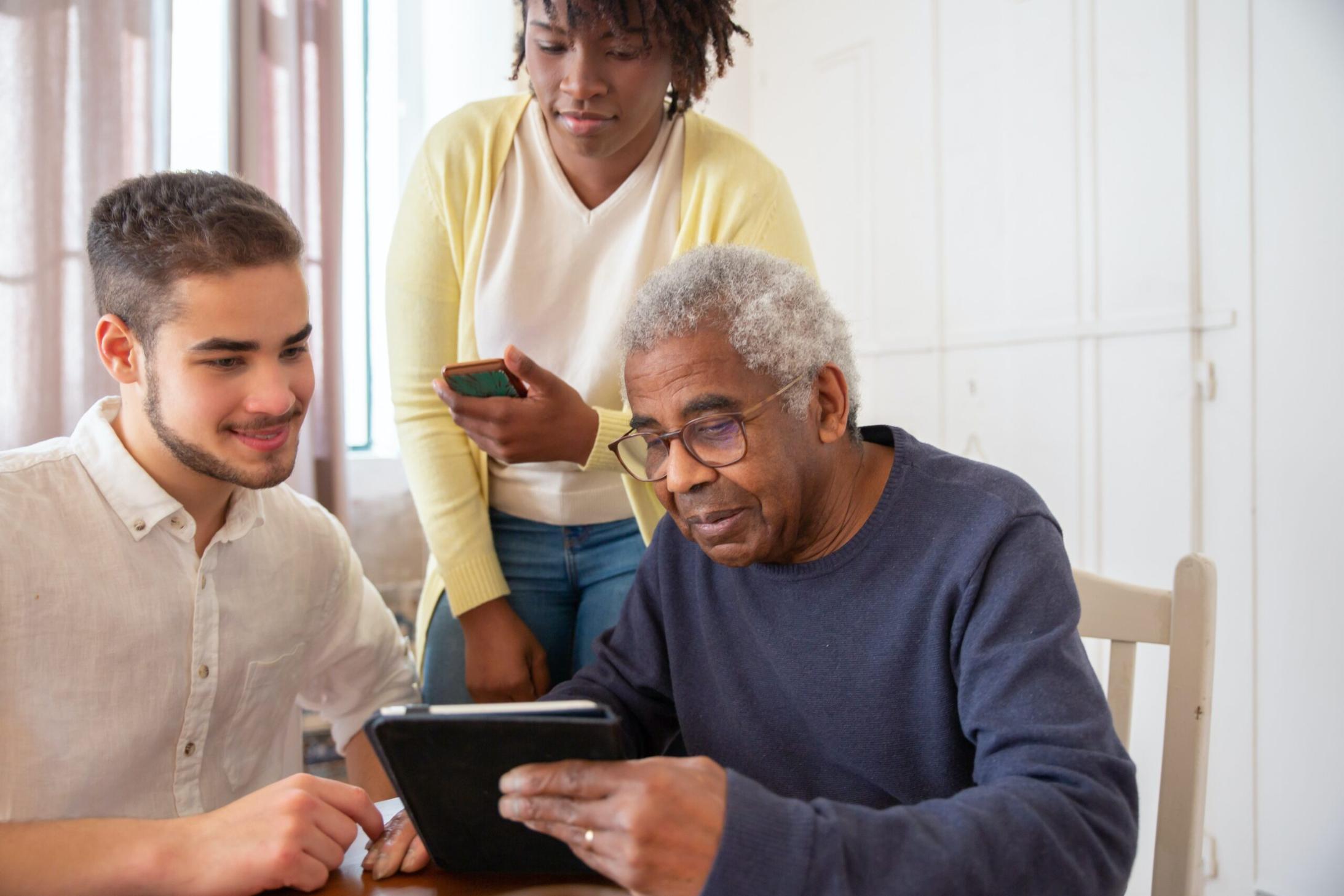 Carer helping elderly people use a tablet