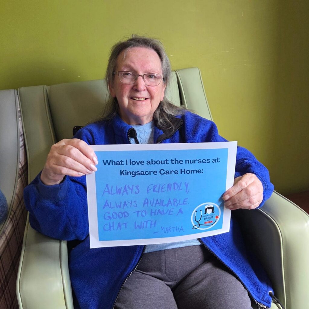 Resident holding up a sign that says: "What I love about the nurses at Kingsacre care home: Always friendly, always available, good to have a chat with."