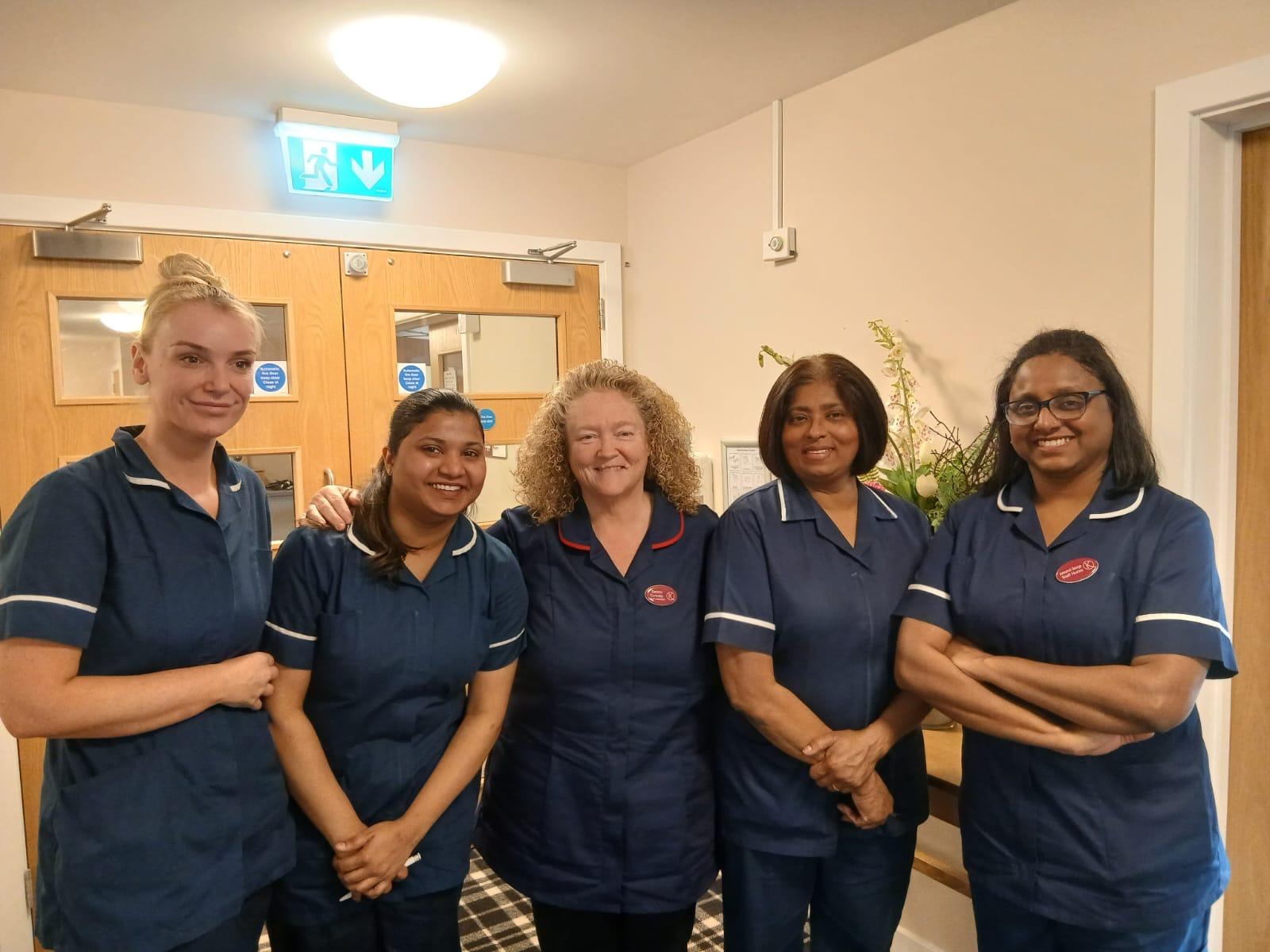 group of female nurses smiling in dark blue uniforms