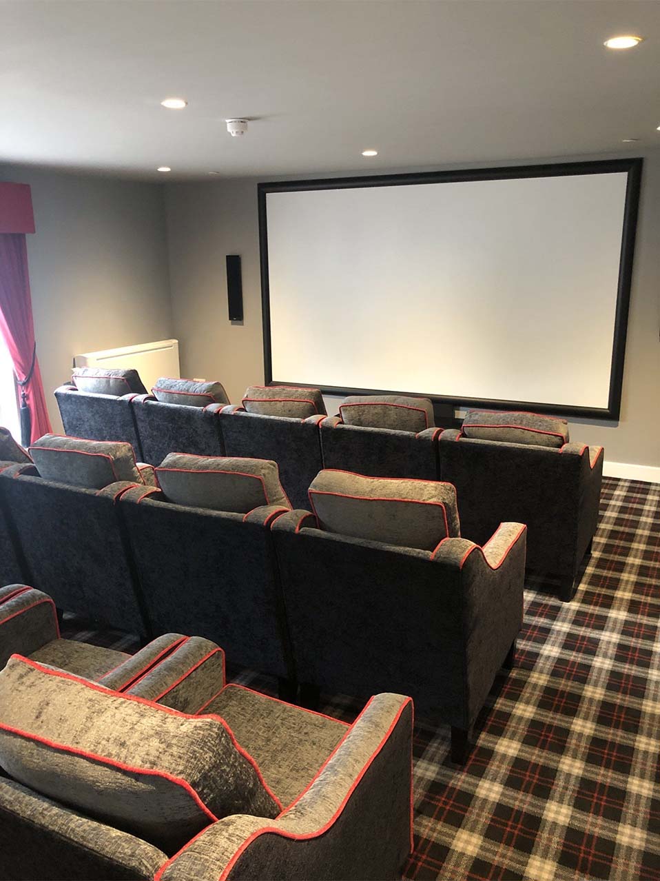 cinema room with large comfy chairs facing a big screen