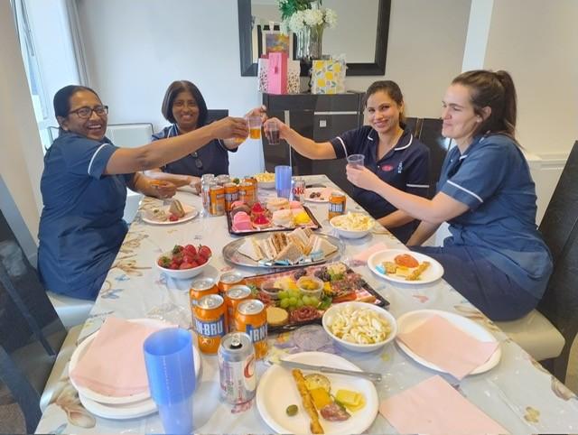 group of nurses in blue uniforms celebrating with an afternoon tea
