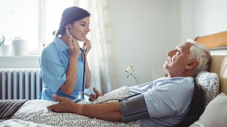 nurse caring for a care home resident lying in bed
