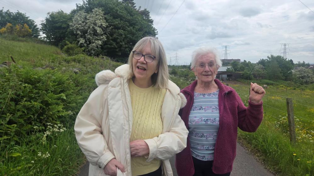 two older ladies standing outside by a field
