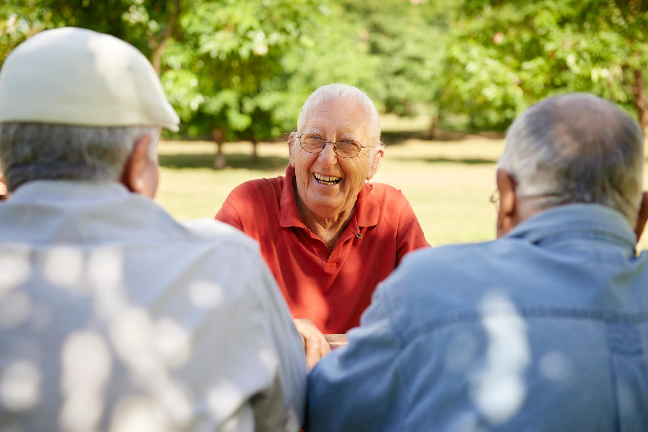 three elderly men laughing together outdoors